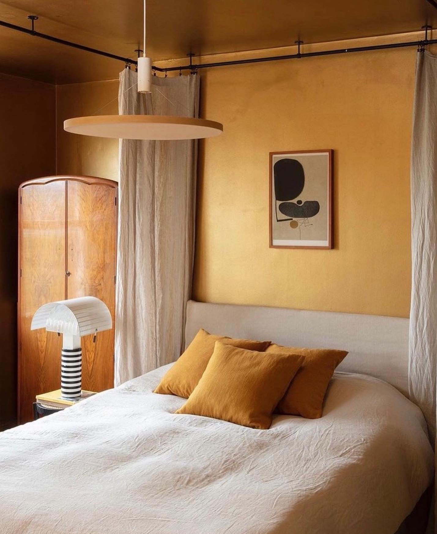 Modern table lamp with a black and white striped cylindrical base and off-white shade, placed on a small table next to a gray sofa with colorful cushions.