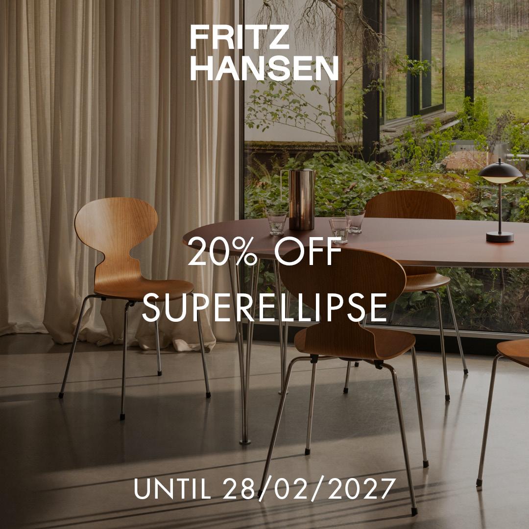 Four stackable wooden chairs with metal legs and an oval wooden table, with glasses, a carafe, and a small black table lamp in a modern dining room setting.