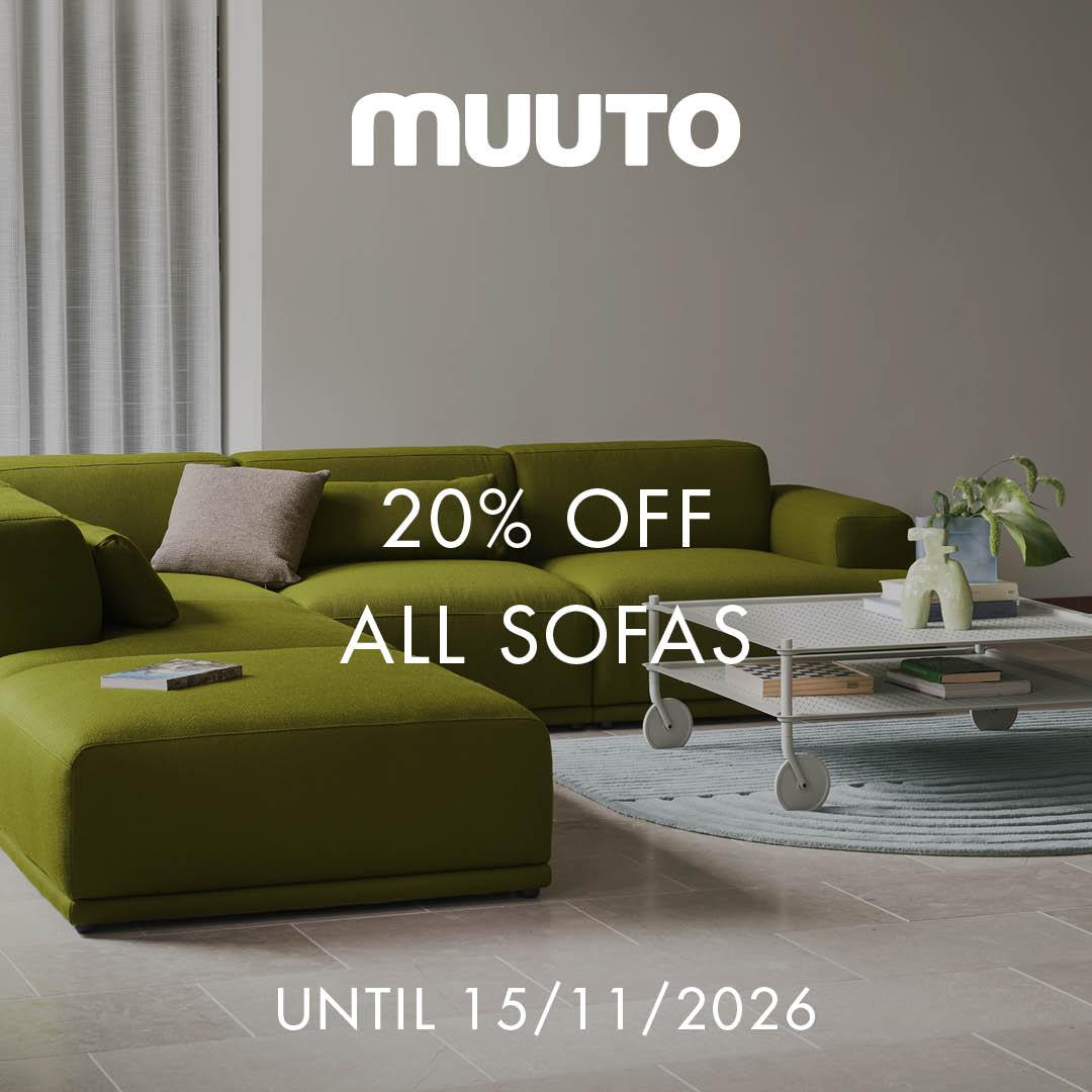 Green modern sectional sofa with a beige cushion, accompanied by a white metal coffee table with wheels, placed on a light blue circular rug on a tiled floor.